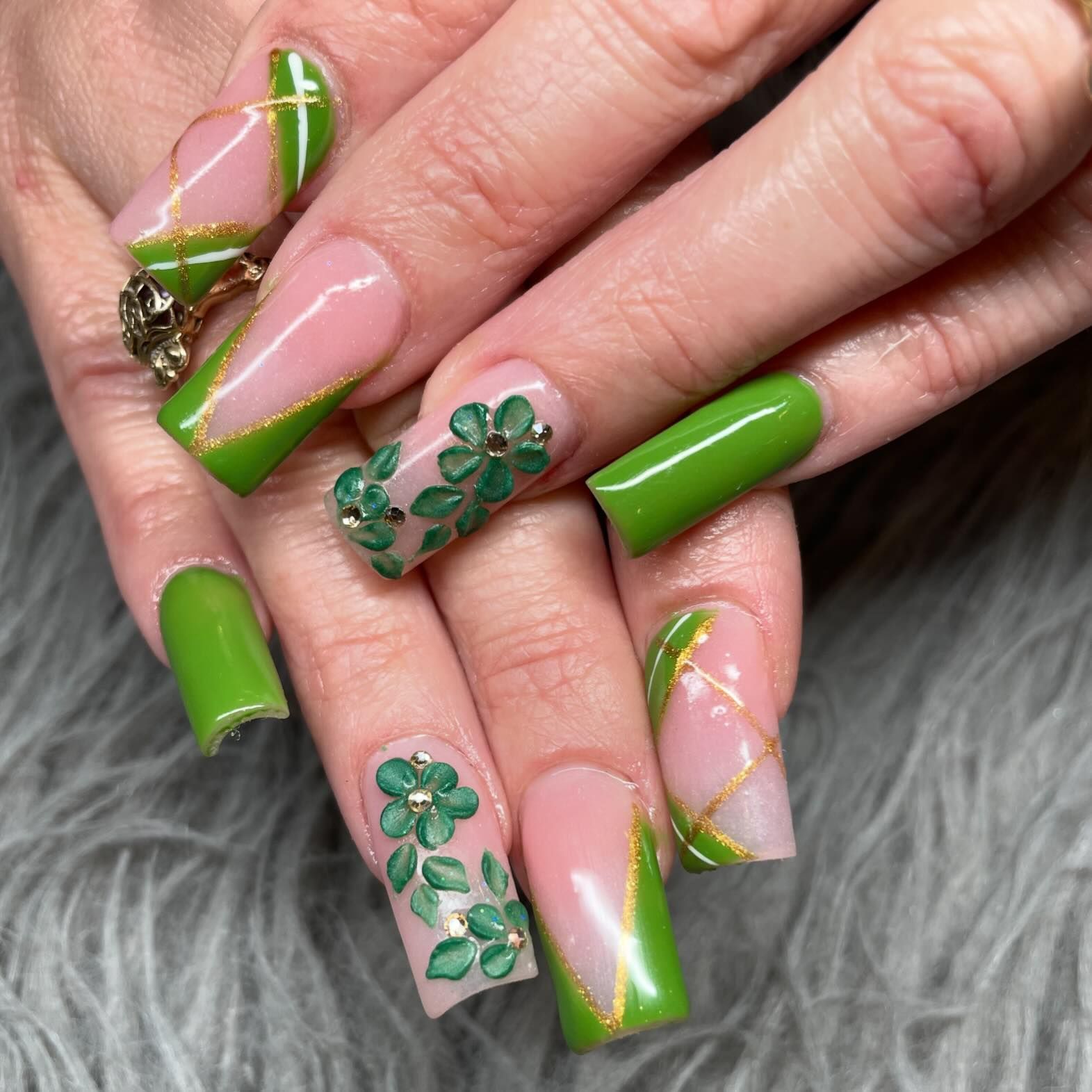 A close up of a woman 's nails with green and pink designs.