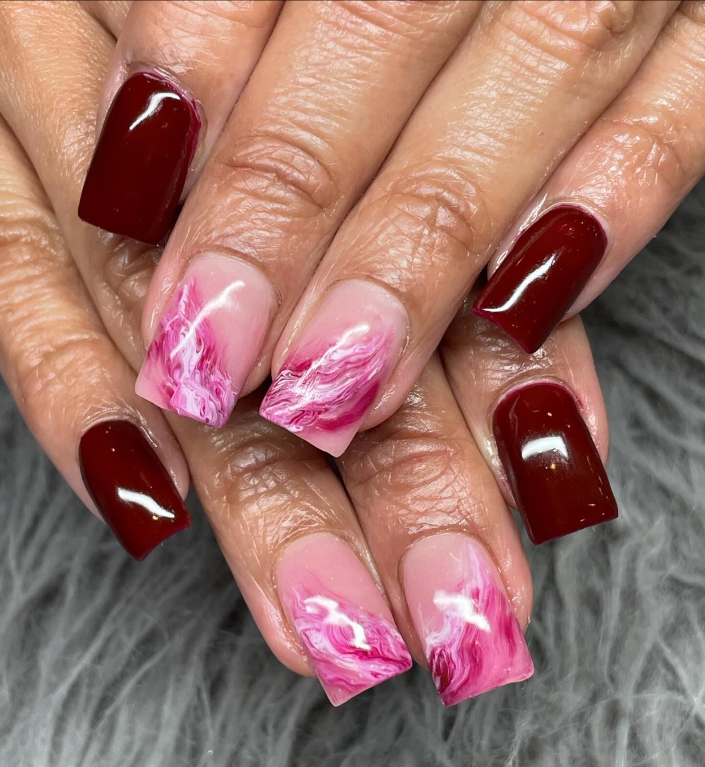 A close up of a woman 's nails with red and pink nail polish