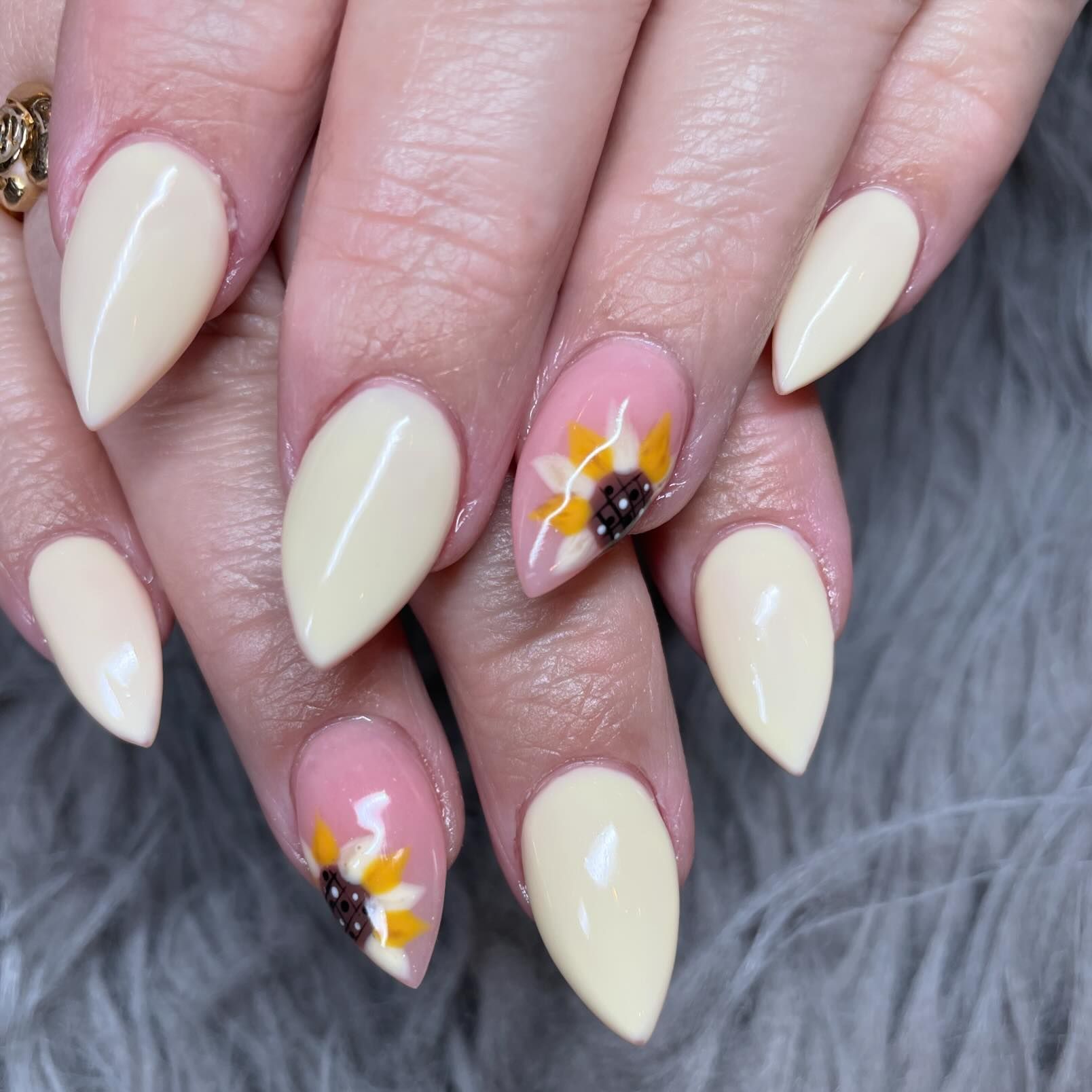 A close up of a woman 's nails with a sunflower design