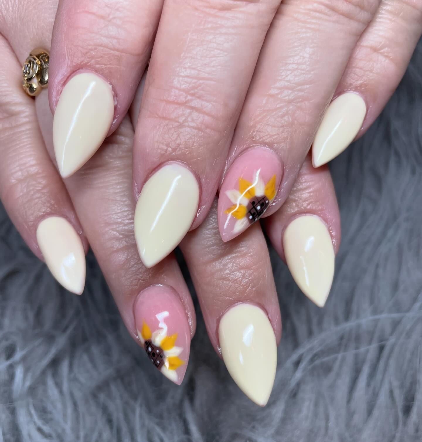 A close up of a woman 's nails with a sunflower design