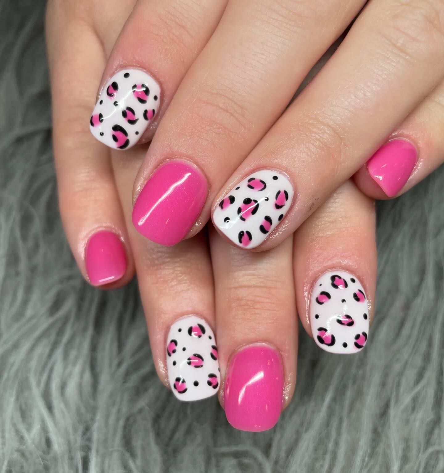 A close up of a woman 's nails with pink and white leopard print