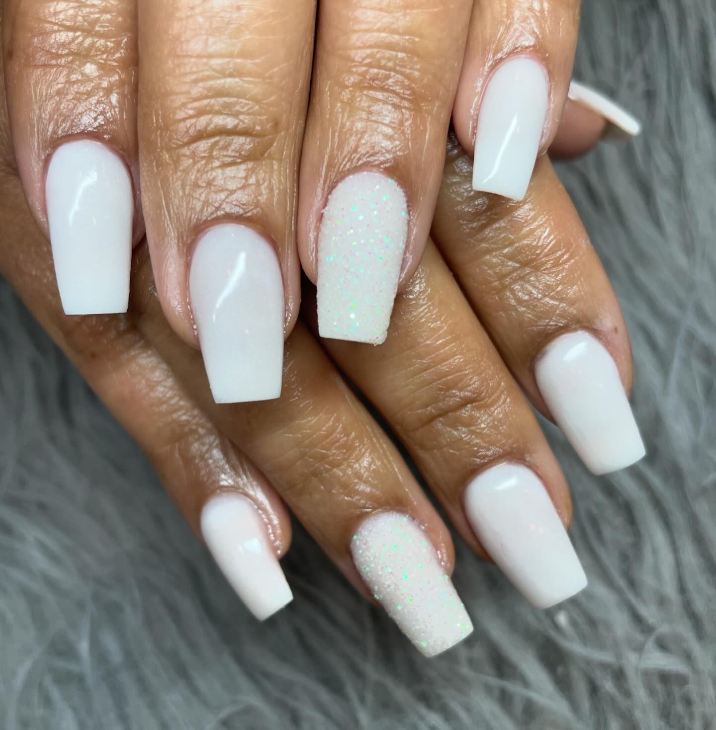 A close up of a woman 's nails with white polish