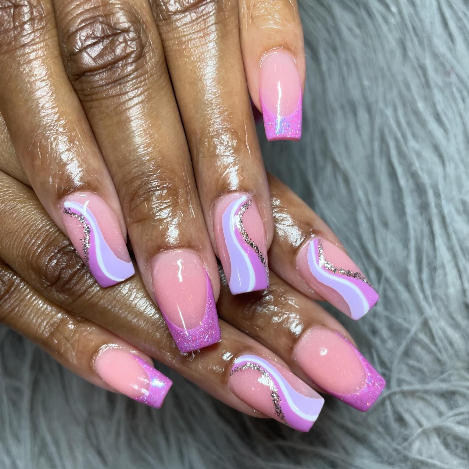A woman 's nails are painted pink and purple with a swirl design.
