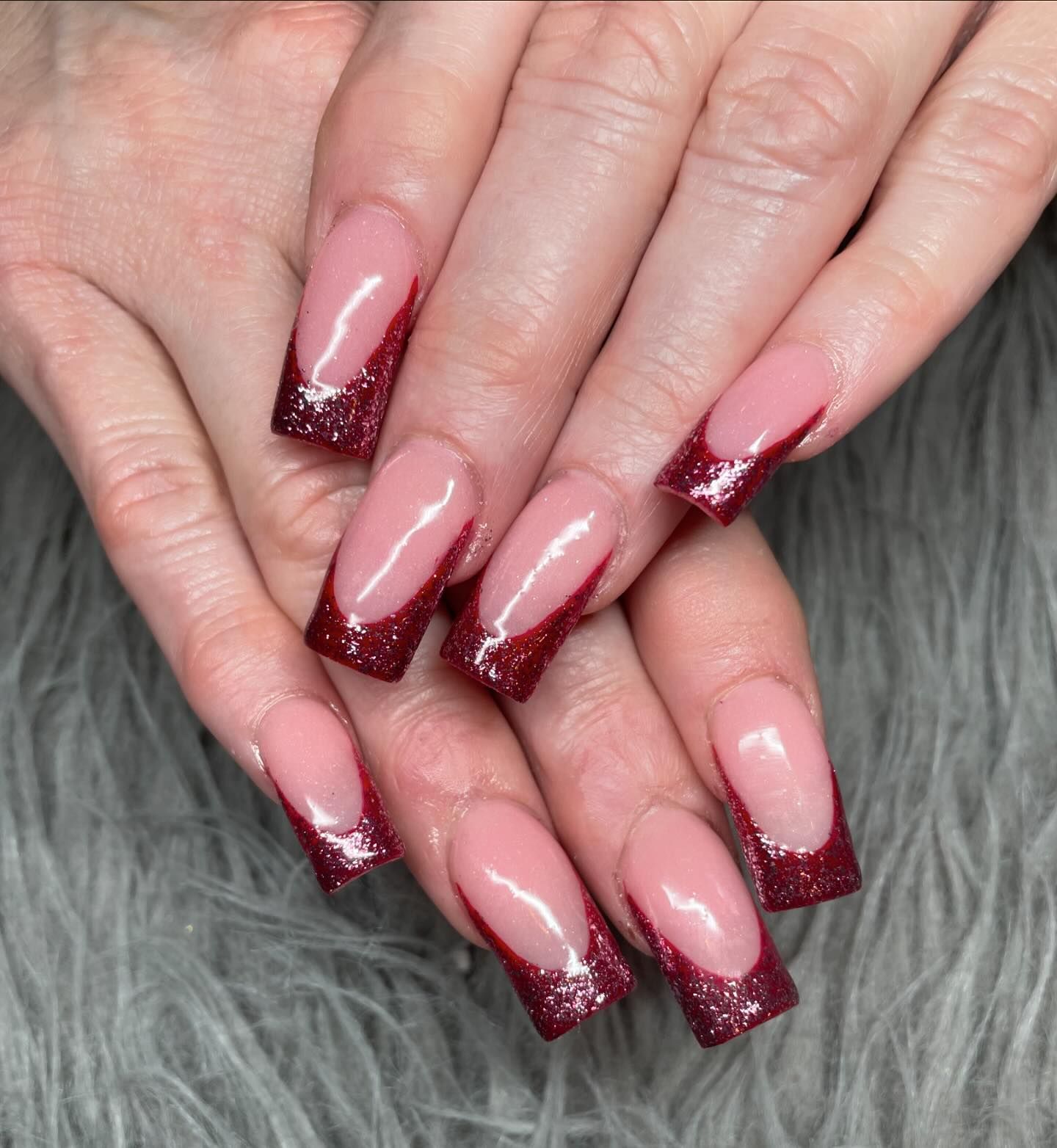 A close up of a woman 's nails with a red french manicure