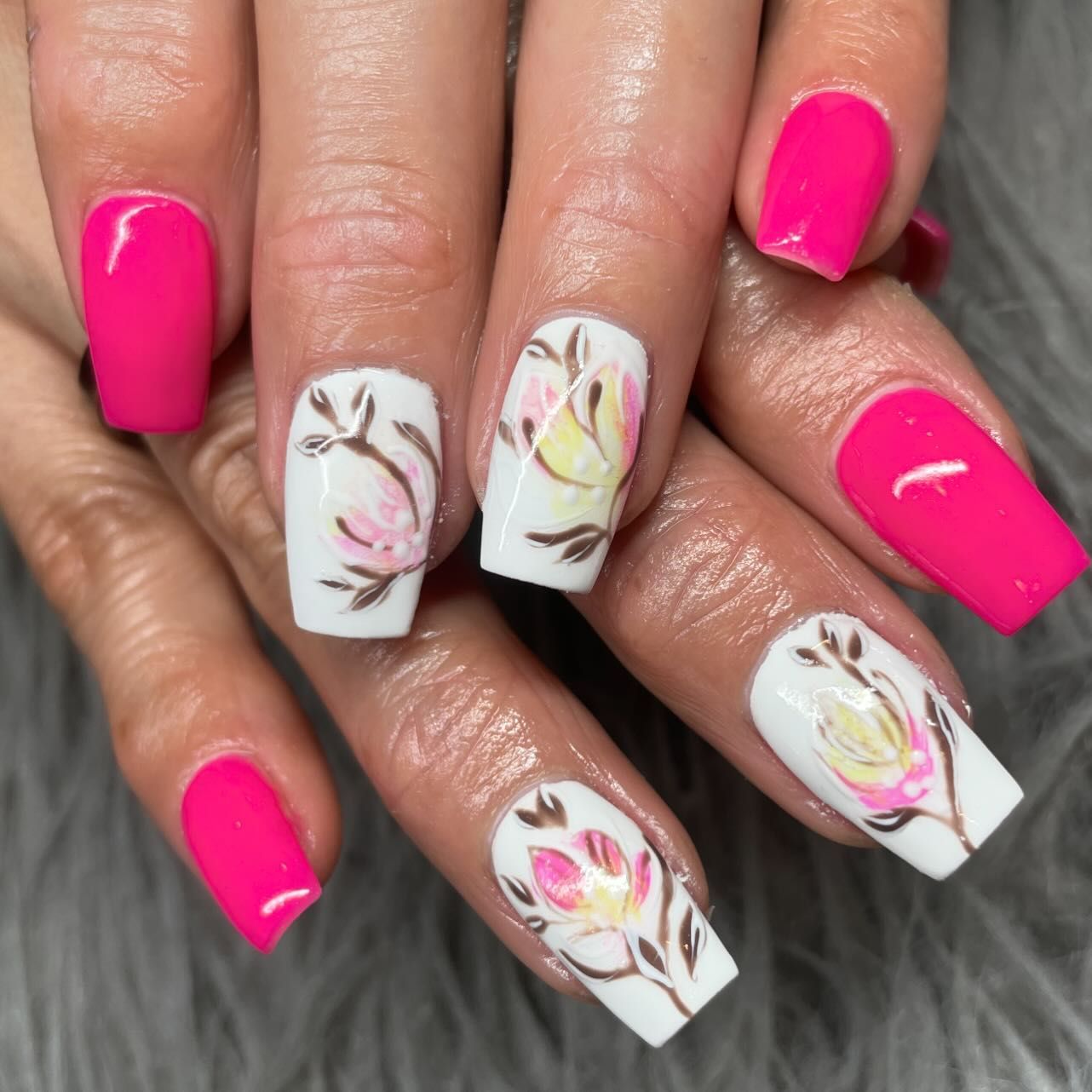 A woman 's nails are painted pink and white with flowers on them.