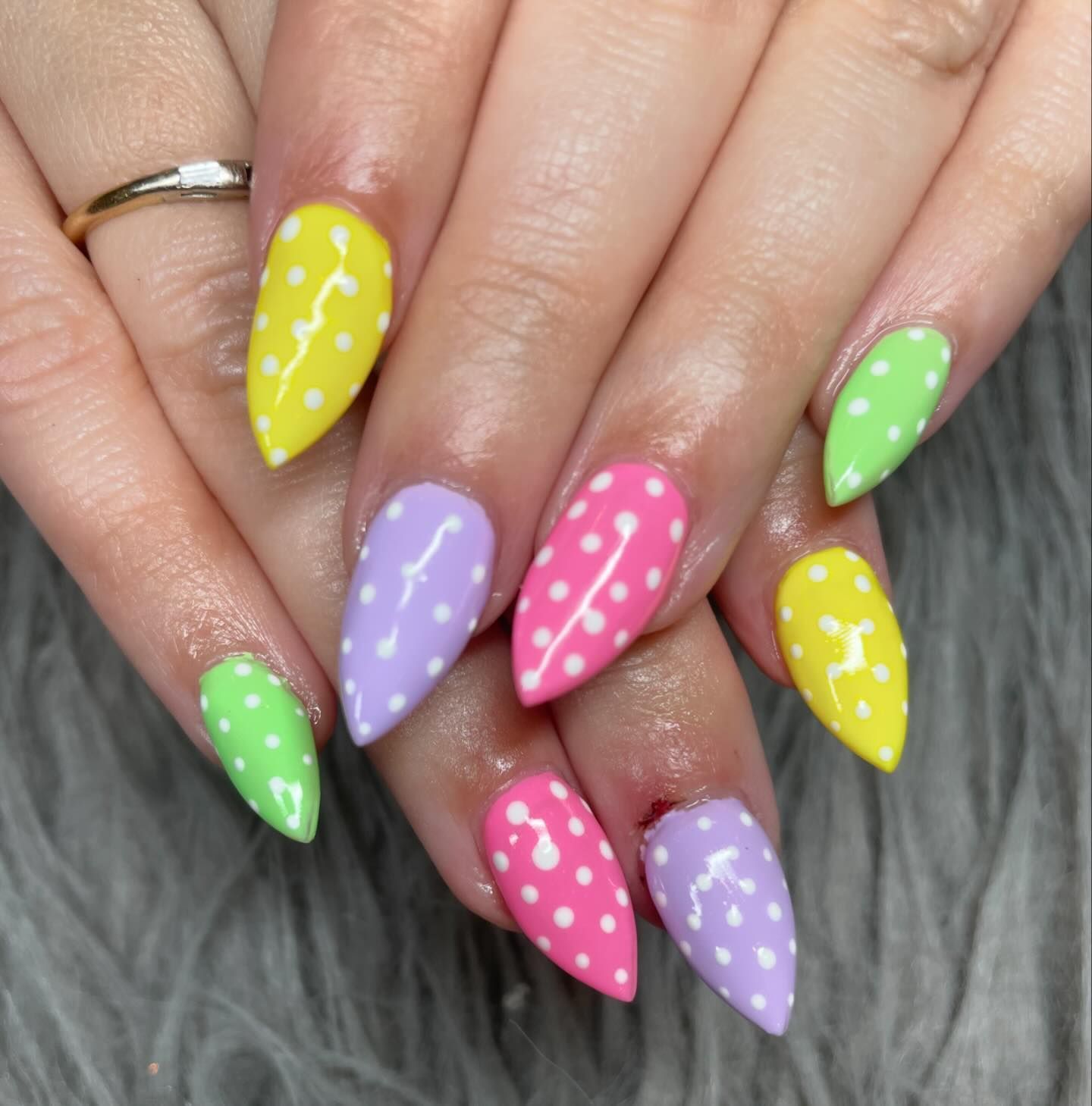 A woman 's nails are painted in different colors with white polka dots