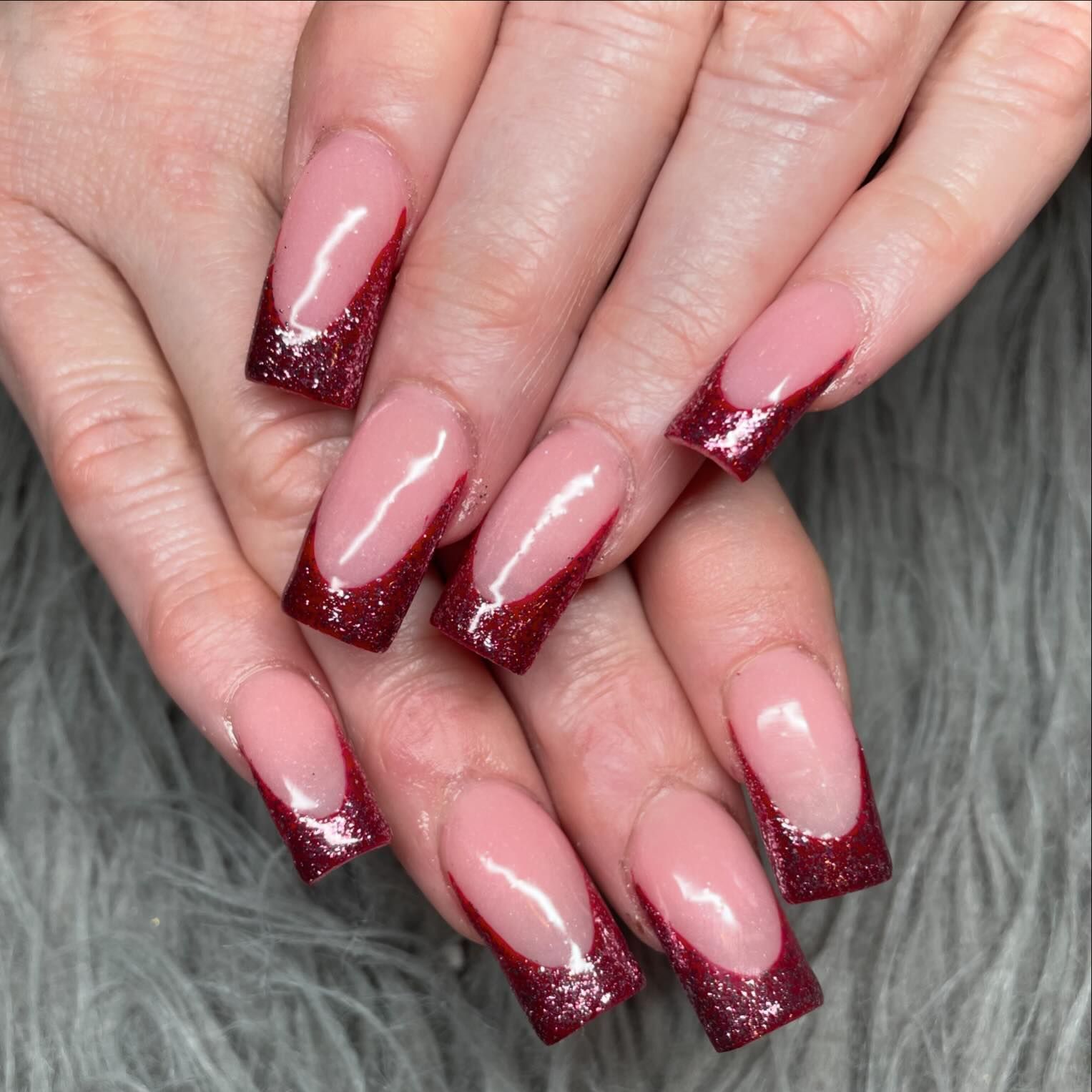 A close up of a woman 's nails with a red french manicure