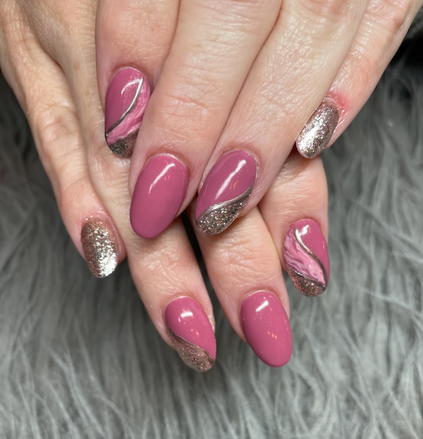 A close up of a woman 's nails with pink and silver designs