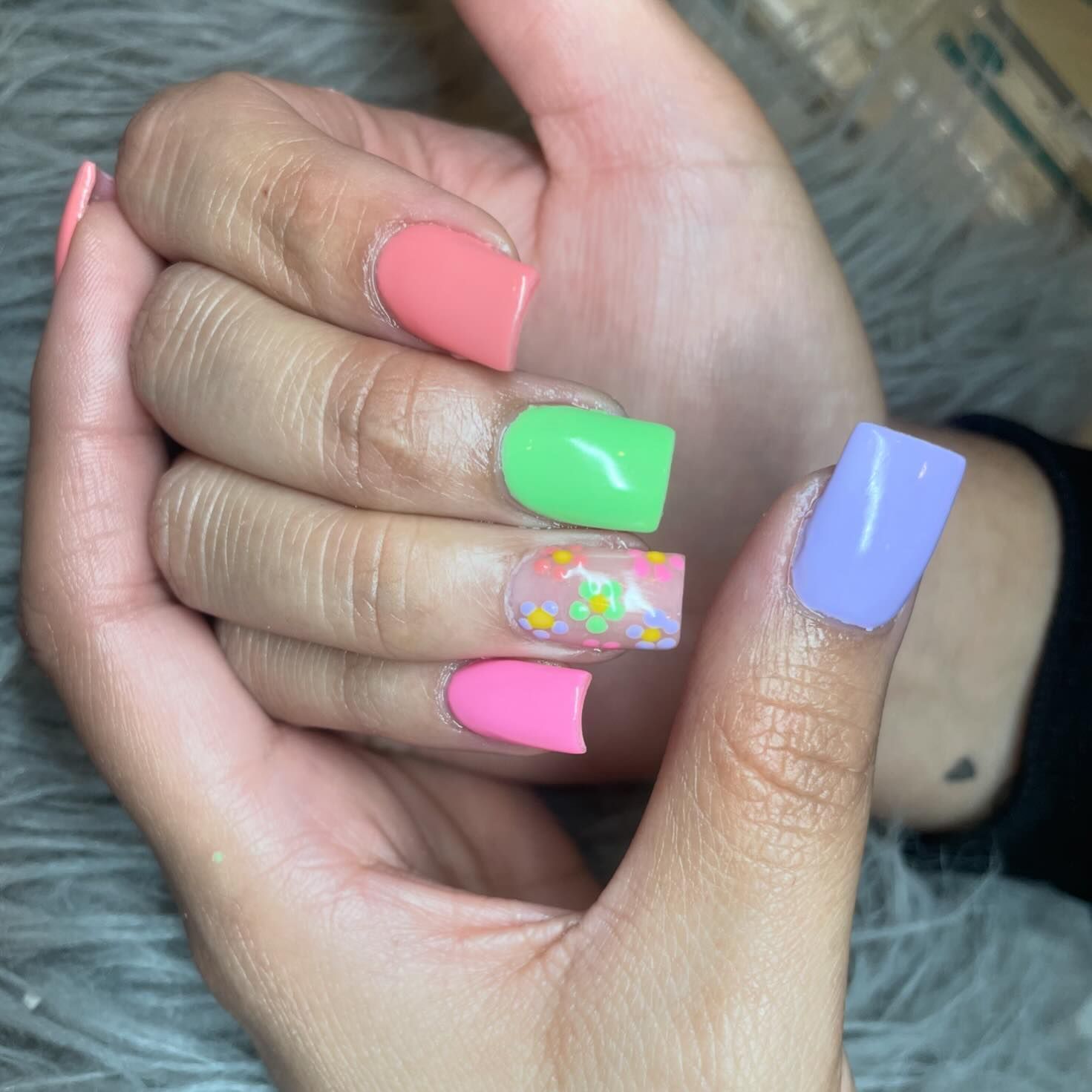 A close up of a woman 's hands with colorful nails