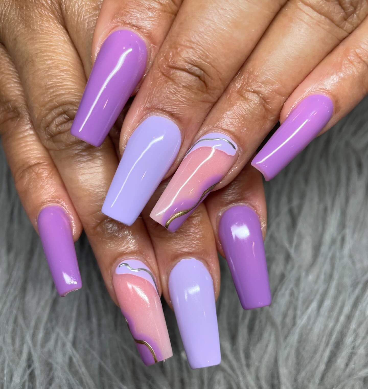A close up of a woman 's nails with purple and pink polish