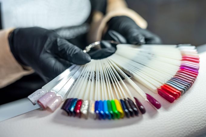 A person wearing black gloves is holding a fan of fake nails.