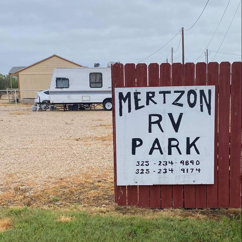 A sign for mertzon rv park is on a red fence