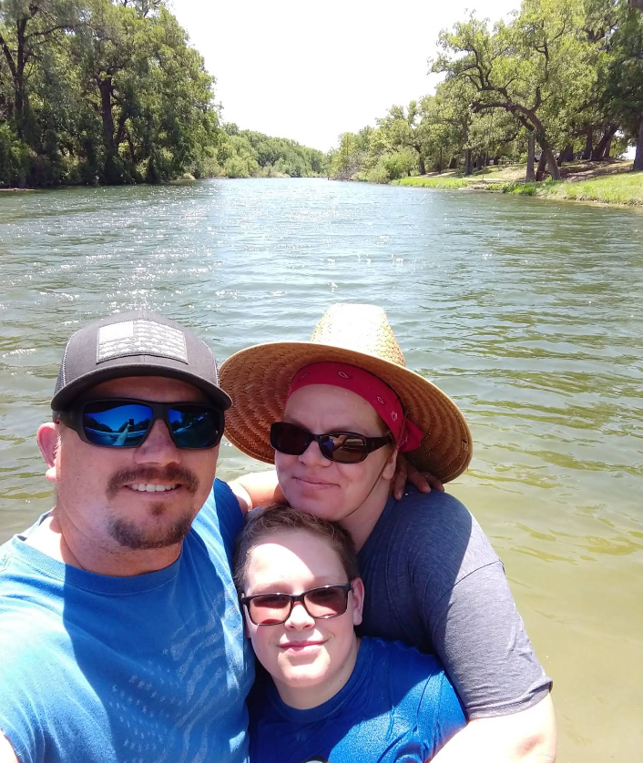 A man a woman and a boy are posing for a picture in the water