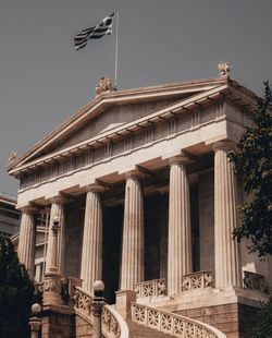 A large building with columns and a flag on top of it.