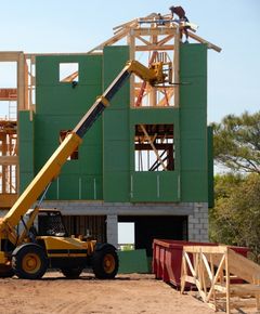 A yellow crane is lifting a green building