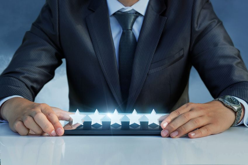Man in suit holding tablet with glowing stars, emphasizing rating.