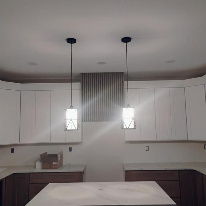 Kitchen with white cabinets, light fixtures, and a wooden accent above the island.