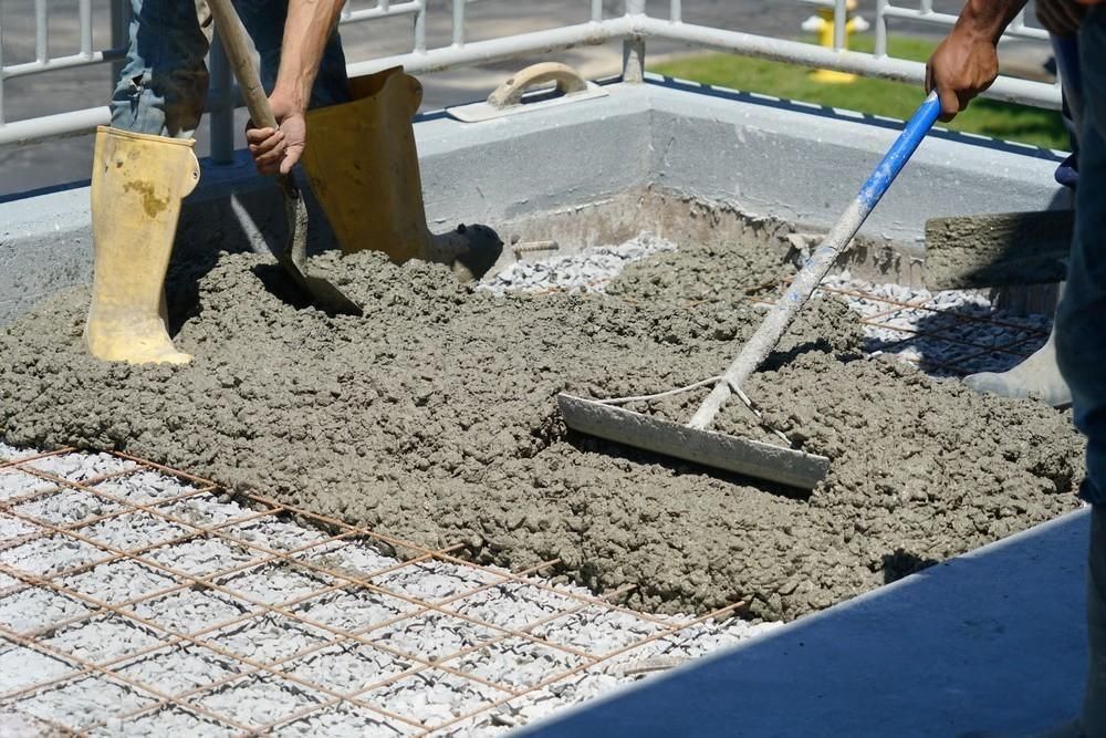 a man is spreading concrete with a rake and shovel
