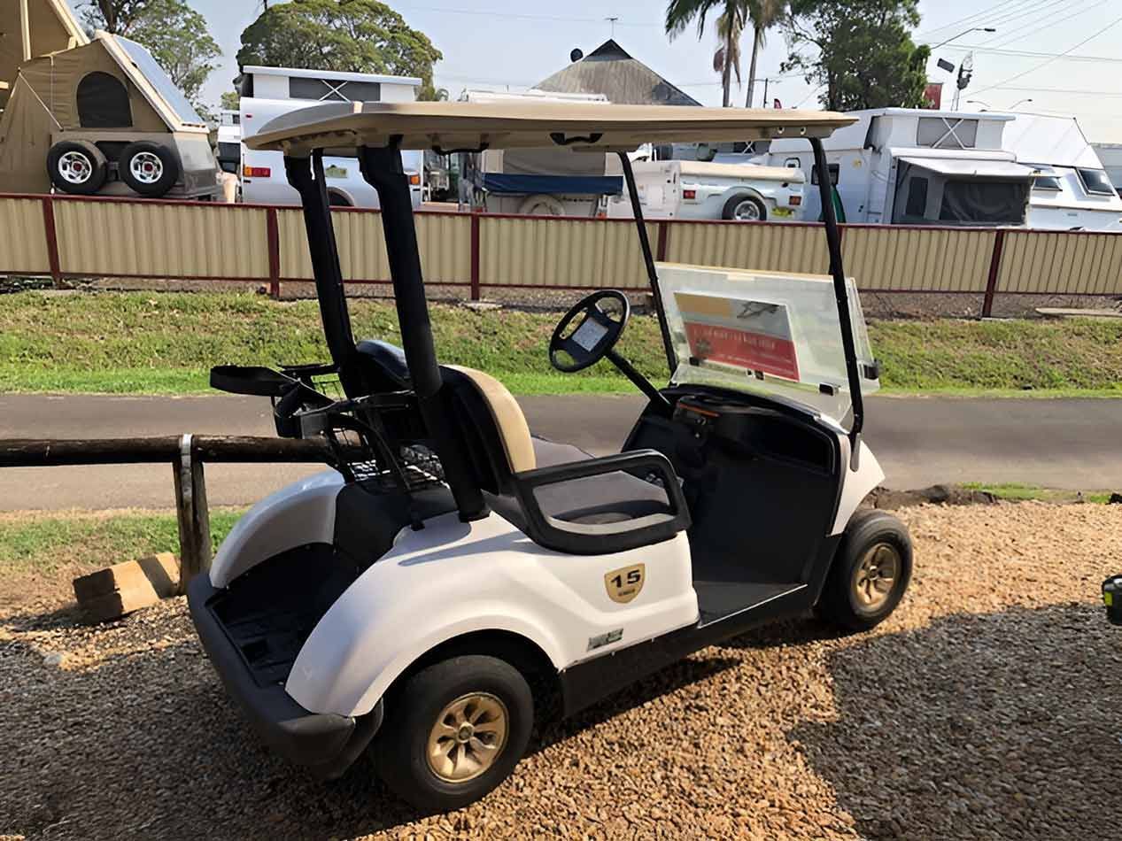 A White Golf Cart Is Parked In Front Of A Fence — Perkins Caravans in Ballina, NSW