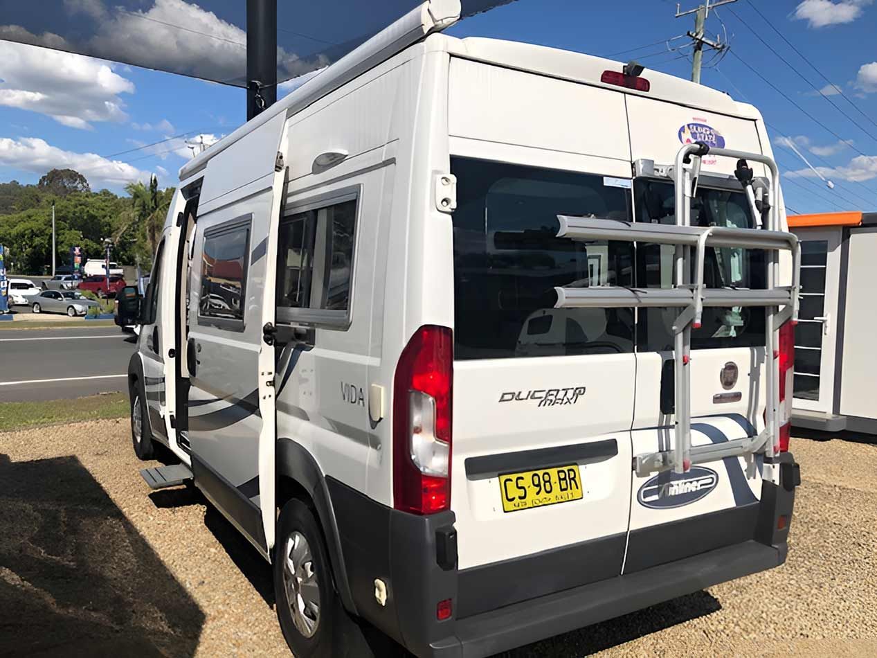 A White Van With A Bicycle Rack On The Back Is Parked In A Parking Lot — Perkins Caravans in Lismore, NSW