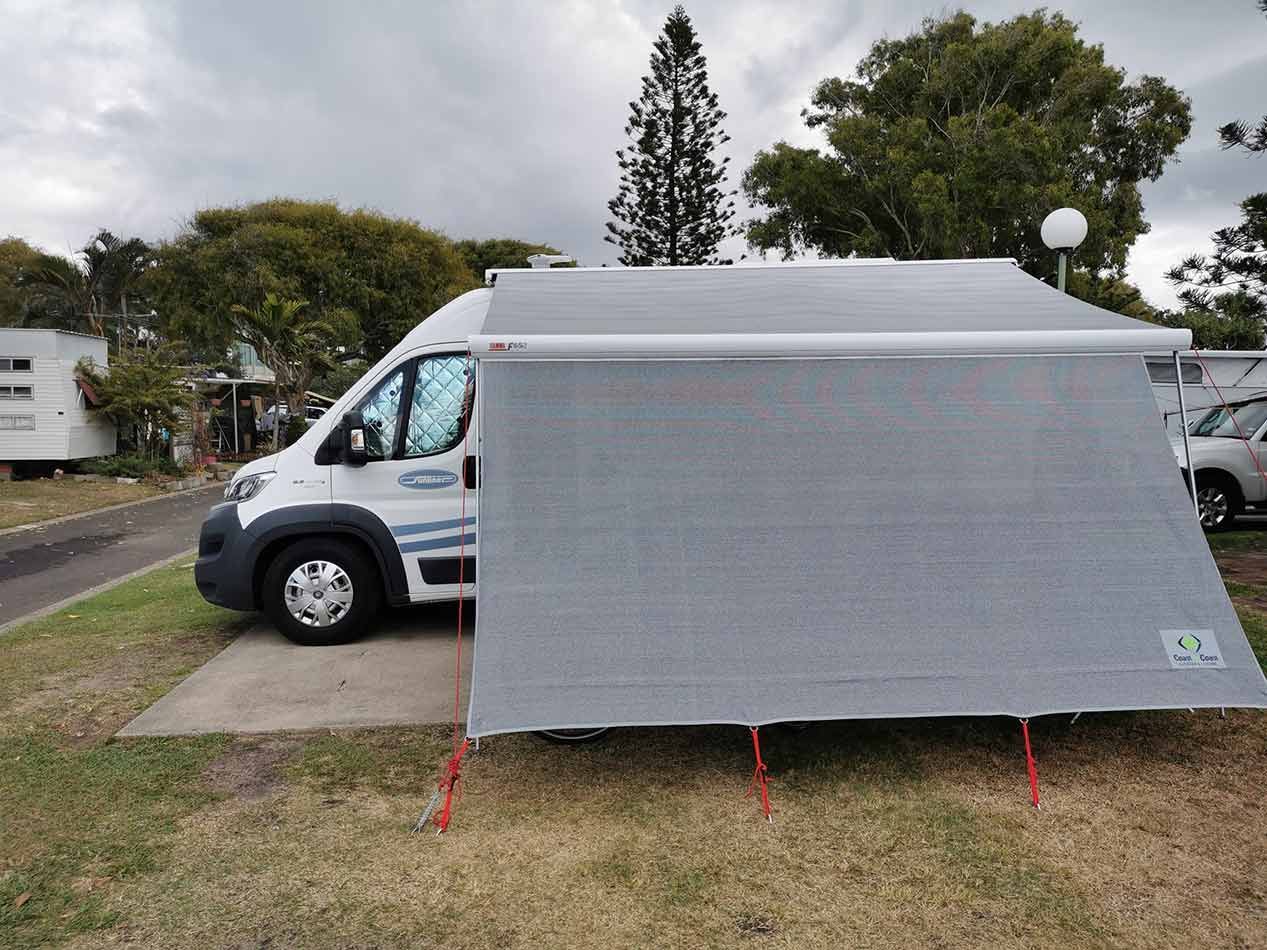 A White Van Is Parked Next To A Tent In A Grassy Area — Perkins Caravans in Lismore, NSW