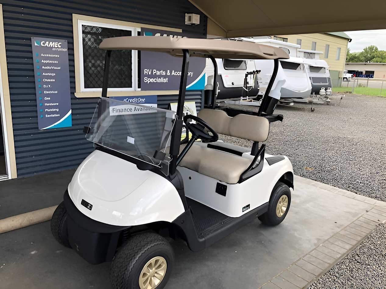 A White Golf Cart Is Parked In Front Of A Building — Perkins Caravans in Ballina, NSW