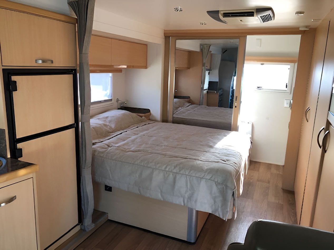 A Bedroom In A Camper With A Bed And A Refrigerator — Perkins Caravans in Lismore, NSW