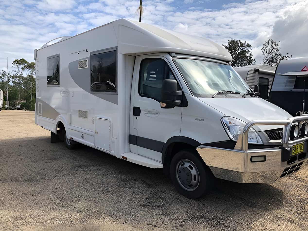 A White Motorhome Is Parked In A Gravel Lot — Perkins Caravans in Grafton, NSW
