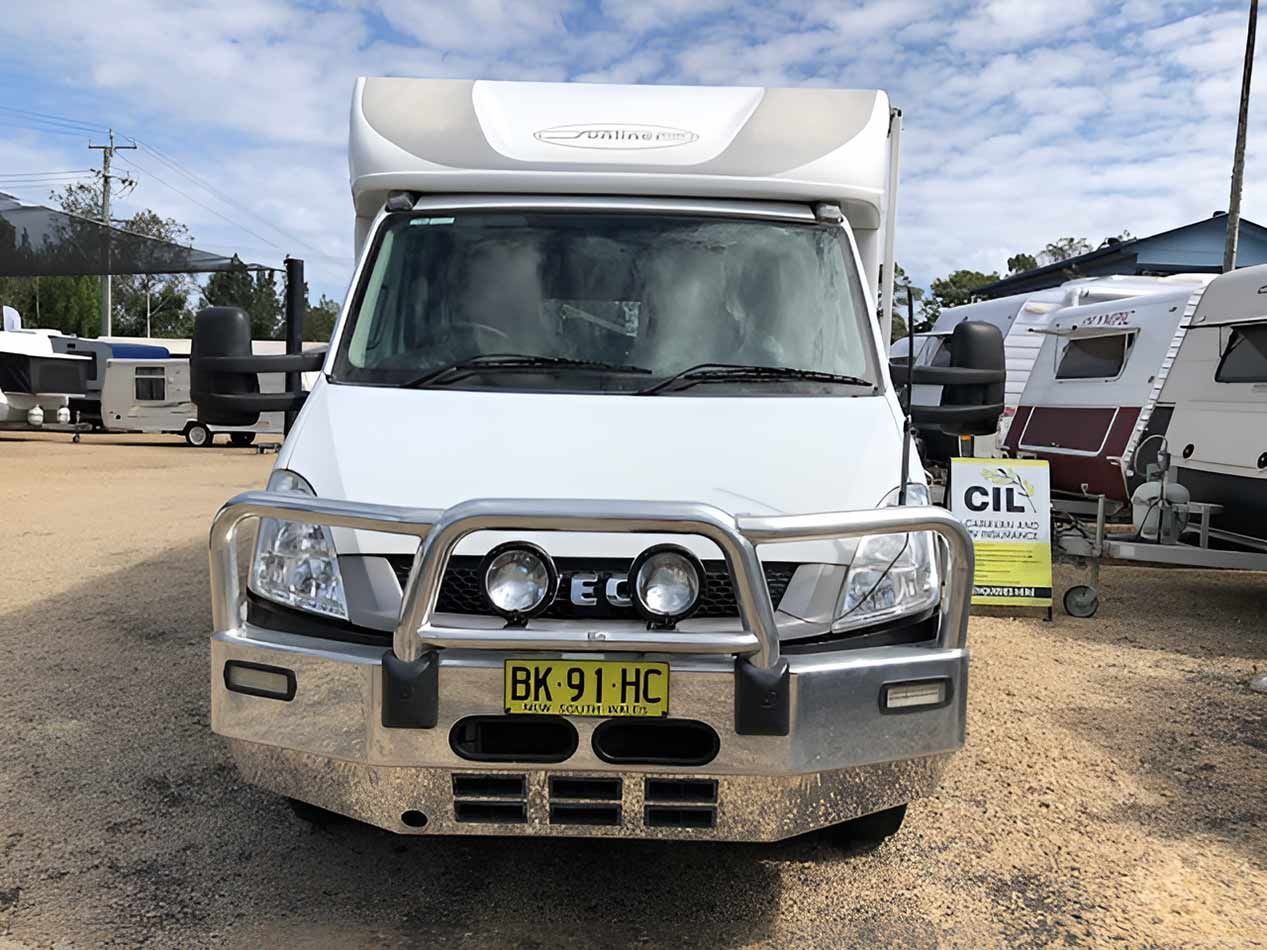 A White Motorhome With A Chrome Bumper Is Parked In A Parking Lot — Perkins Caravans in Ballina, NSW