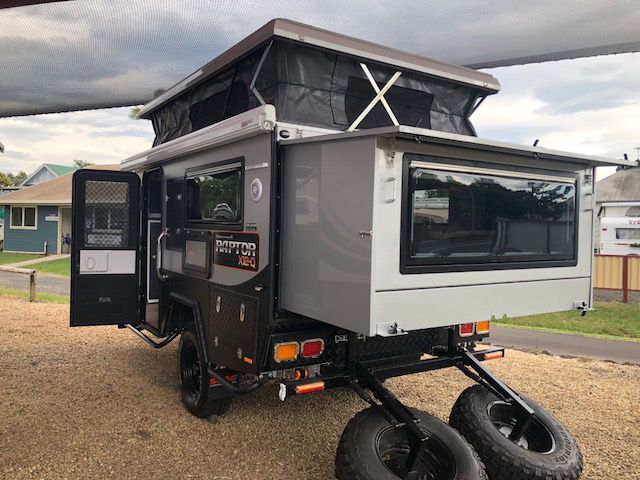 A Camper Trailer With A Pop Up Roof Is Parked In A Gravel Lot — Perkins Caravans in Ballina, NSW