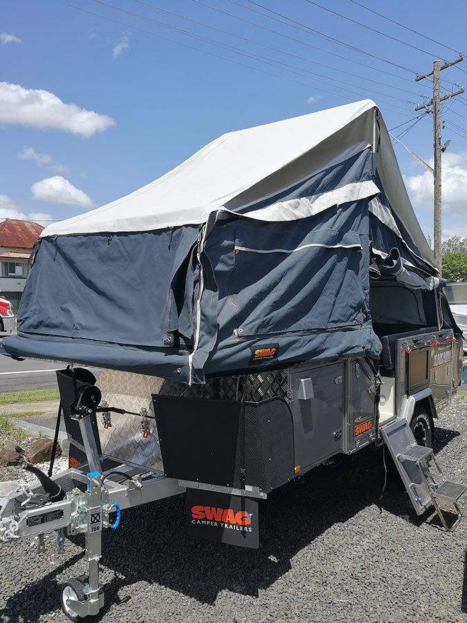 A Trailer With A Tent On Top Of It Is Parked On The Side Of The Road — Perkins Caravans in Ballina, NSW