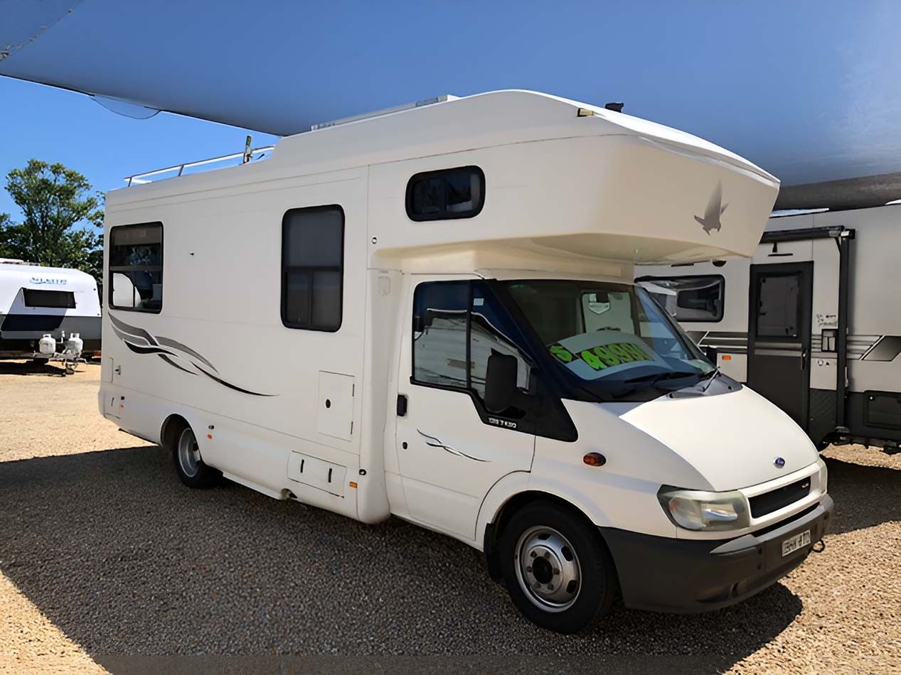 A White Motorhome Is Parked In A Gravel Lot — Perkins Caravans in Grafton, NSW