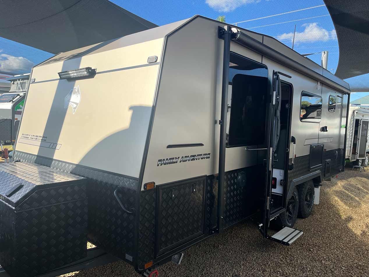 A White And Black Trailer Is Parked In A Gravel Lot — Perkins Caravans in Byron Bay, NSW
