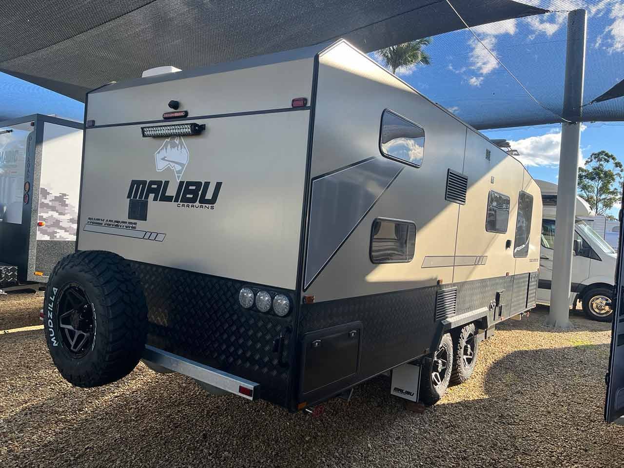 A White Caravan Is Parked Under A Canopy In A Gravel Lot — Perkins Caravans in Yamba, NSW