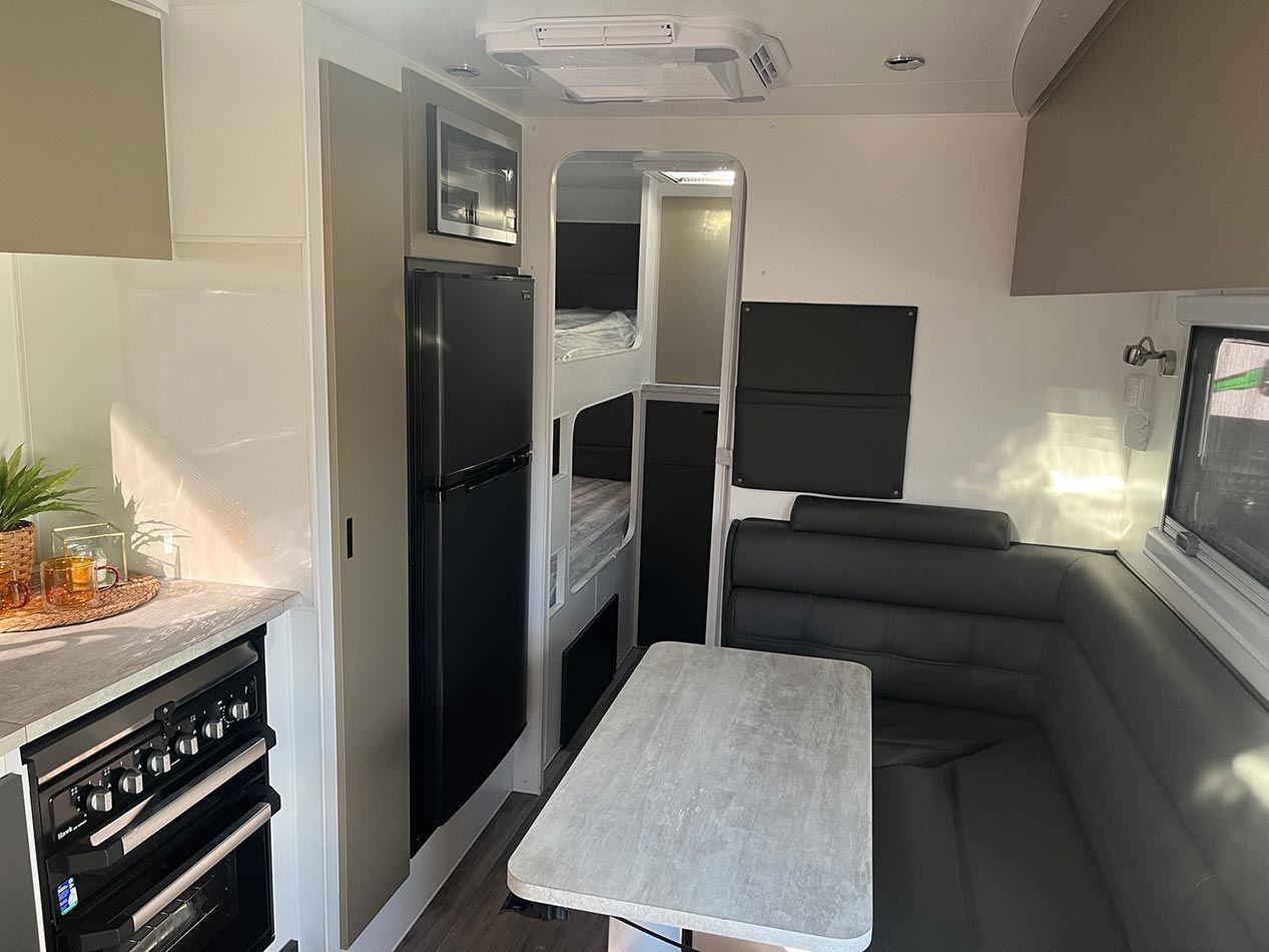 A Kitchen In A Camper With A Table And A Refrigerator — Perkins Caravans in Byron Bay, NSW