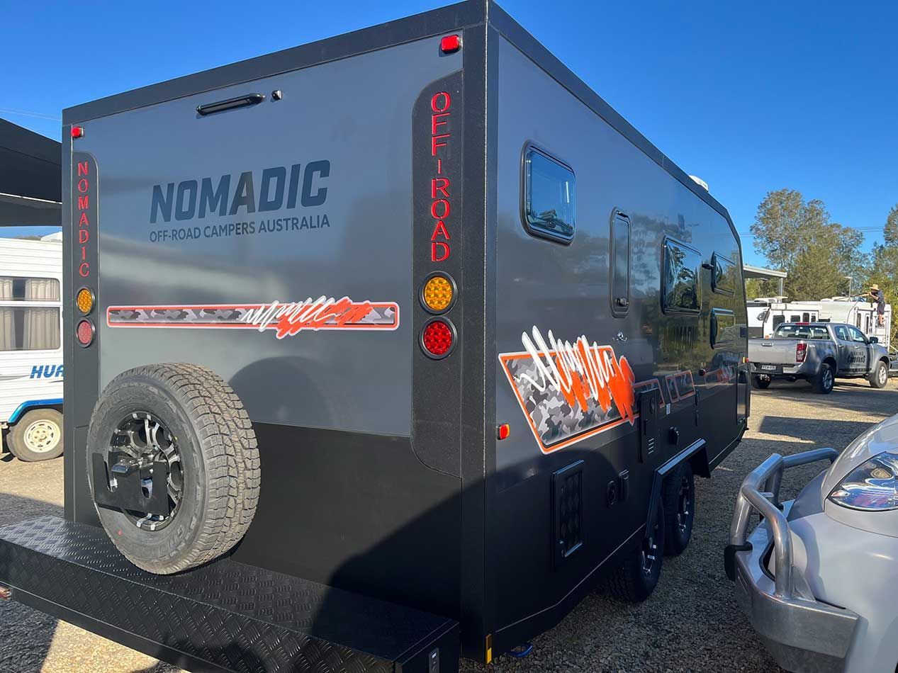A Nomadic Camper Is Parked In A Parking Lot Next To A Car — Perkins Caravans in Lismore, NSW