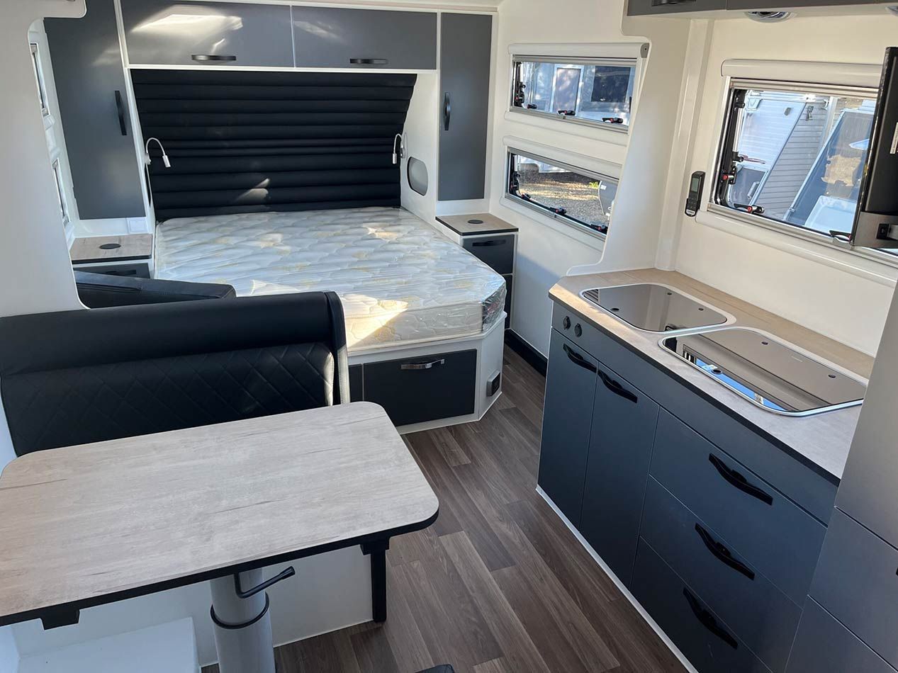 The Inside Of A Camper With A Table And A Bed — Perkins Caravans in Lismore, NSW