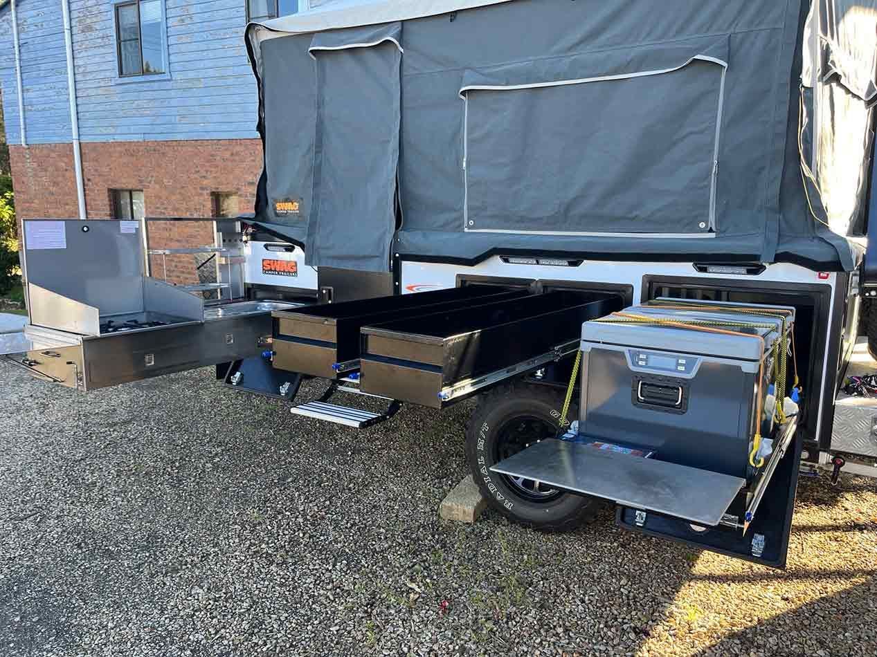 A Camper Trailer Is Parked In A Gravel Lot In Front Of A House — Perkins Caravans in Ballina, NSW