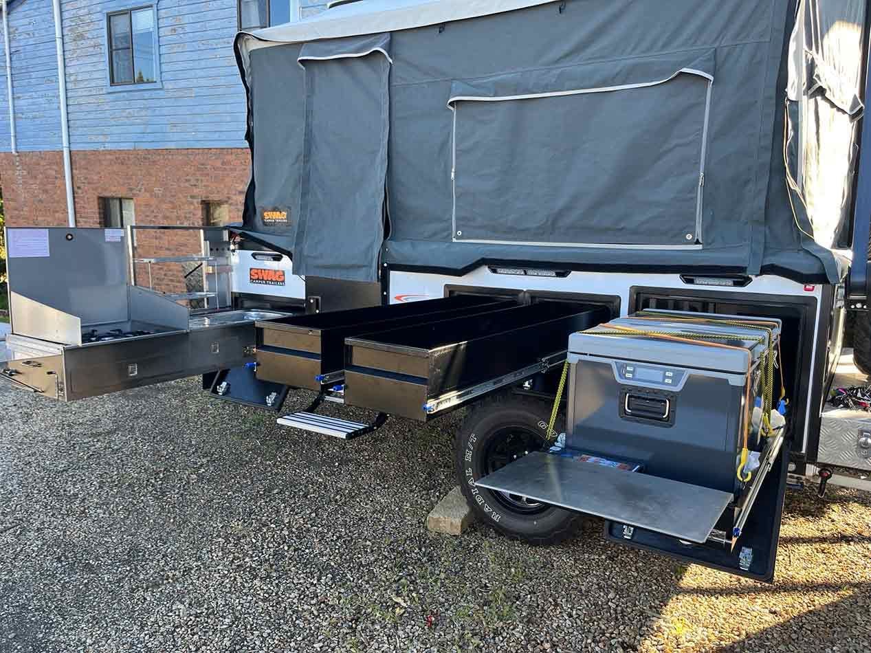 A Camper Trailer Is Parked In A Gravel Lot Next To A Building — Perkins Caravans in Ballina, NSW