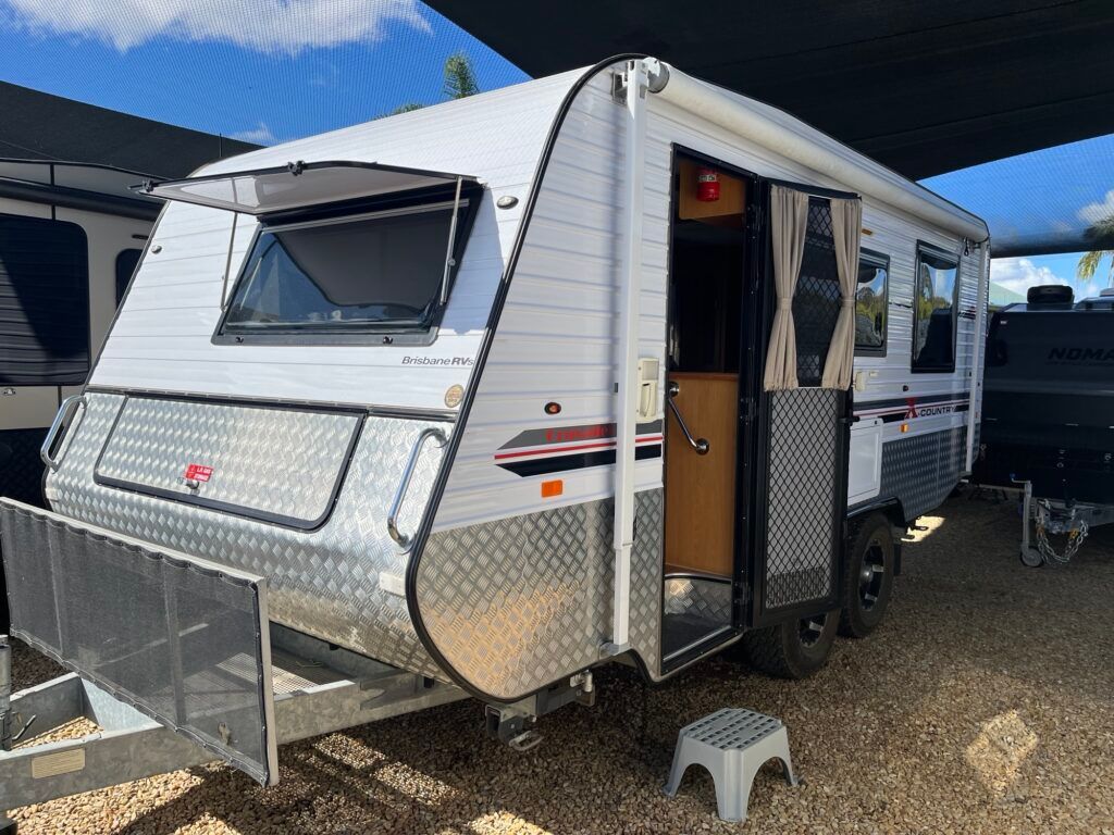 A White Caravan Is Parked In A Gravel Lot Under A Canopy — Perkins Caravans in Ballina, NSW