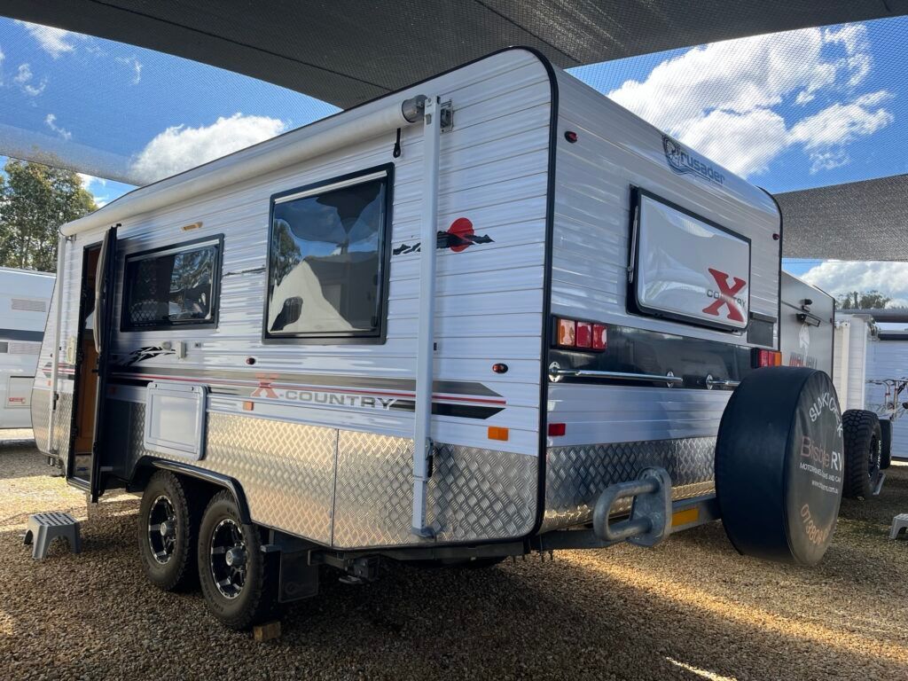 A White Trailer Is Parked Under A Canopy In A Gravel Lot — Perkins Caravans in Ballina, NSW