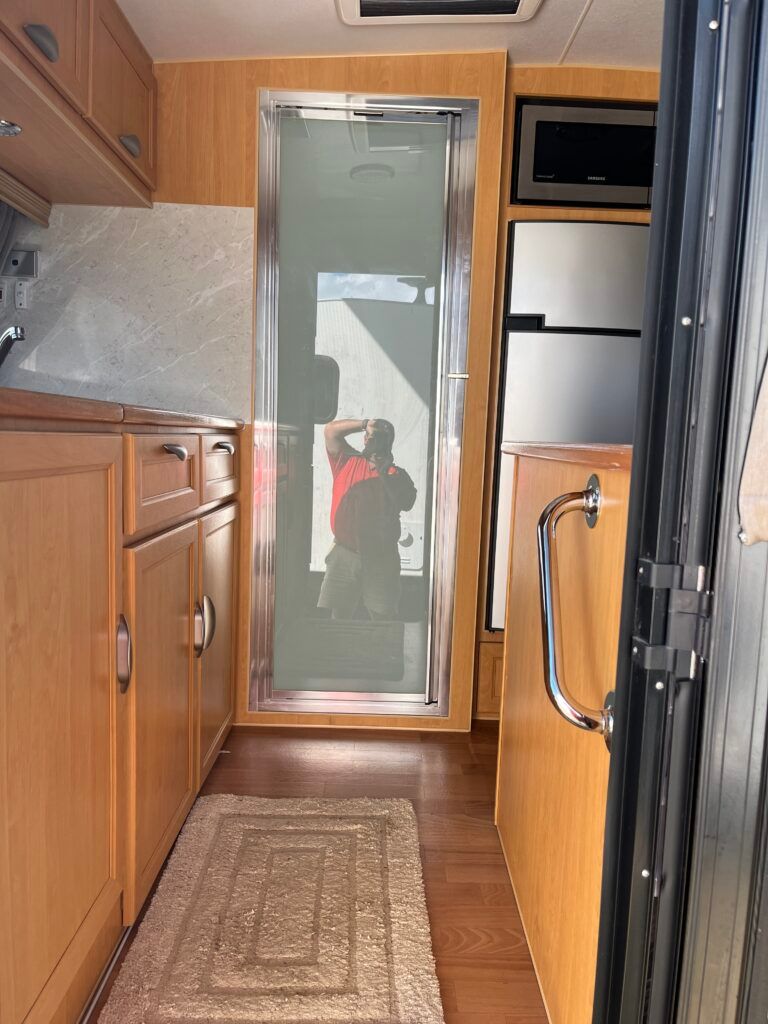 A Kitchen With Wooden Cabinets And A Sliding Glass Door — Perkins Caravans in Ballina, NSW