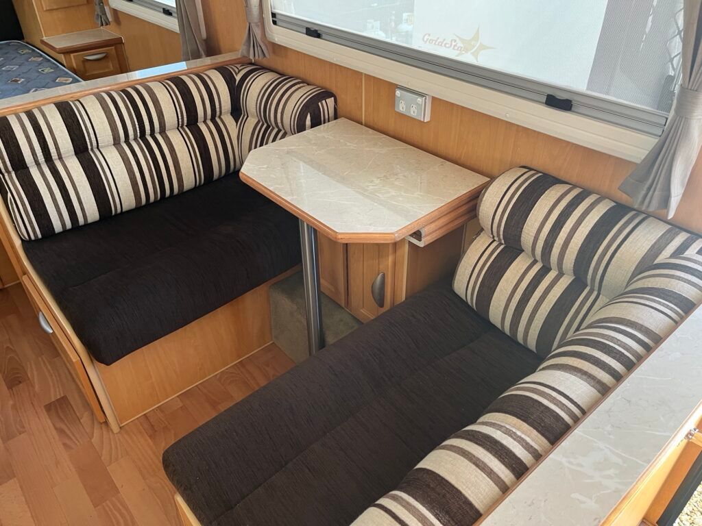 A Living Room In A Camper With Striped Pillows And A Table — Perkins Caravans in Ballina, NSW