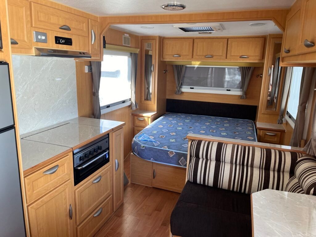 The Inside Of A Camper With A Bed And A Couch — Perkins Caravans in Ballina, NSW