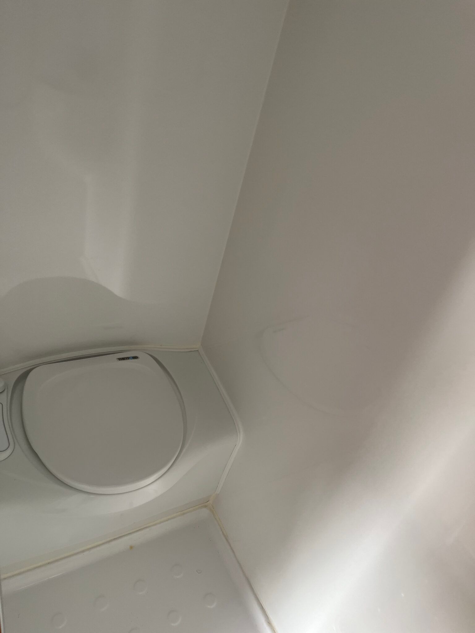 A White Toilet Is Sitting In A Corner Of A Bathroom Next To A White Wall — Perkins Caravans in Ballina, NSW