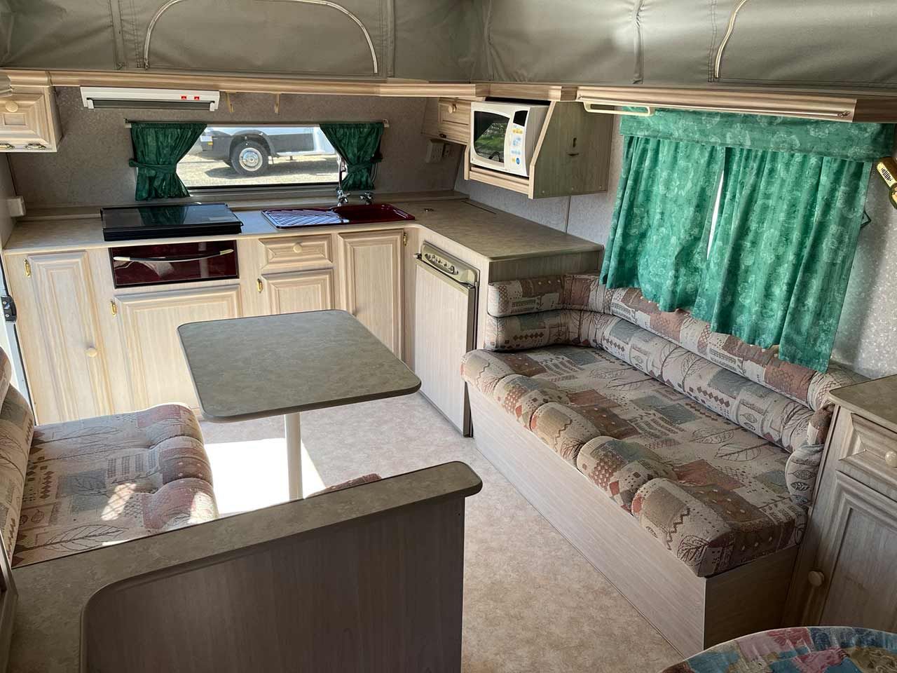 The Inside Of A Camper With A Couch And A Table — Perkins Caravans in Yamba, NSW