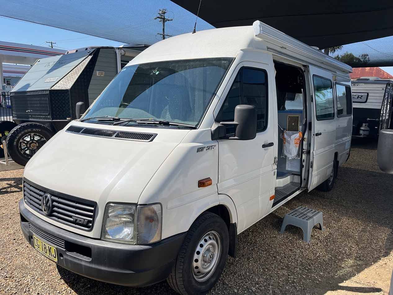 A White Van Is Parked Under A Canopy In A Gravel Lot — Perkins Caravans in Ballina, NSW
