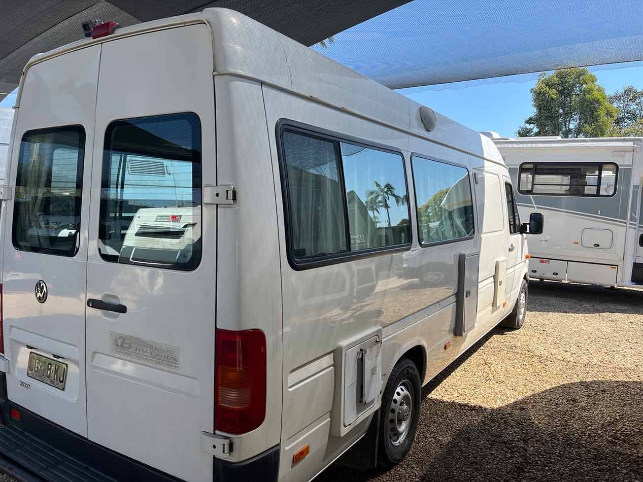 A White Motorhome Is Parked In A Parking Lot Next To A Caravan — Perkins Caravans in Ballina, NSW