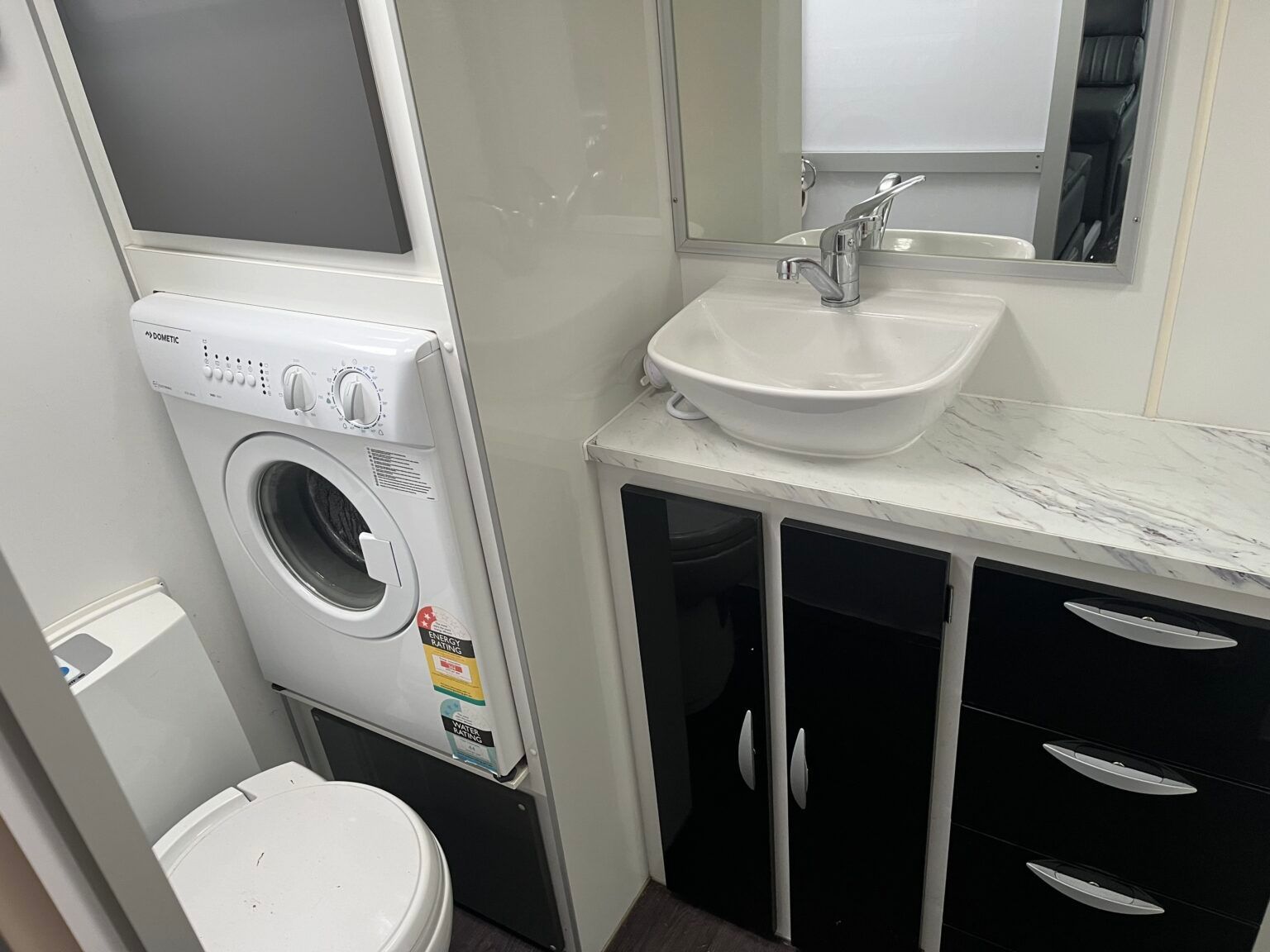 A Bathroom With A Sink, Toilet, Washer And Dryer — Perkins Caravans in Ballina, NSW