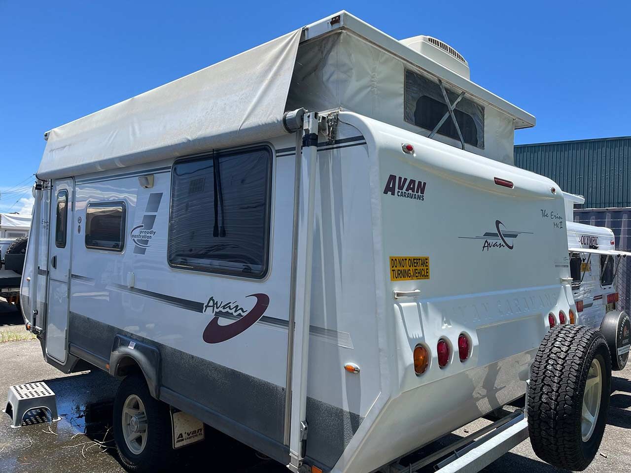 A White Trailer With A Tent On Top Of It Is Parked In A Parking Lot — Perkins Caravans in Yamba, NSW